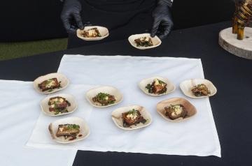 Gloved hands arranging small plates of food on a table
